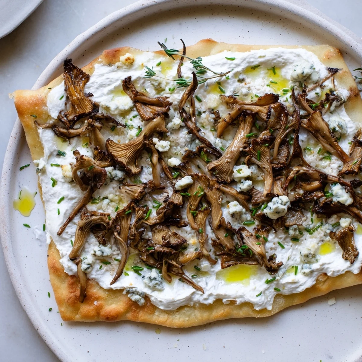 Crispy Tarte Flambée with oyster mushrooms, bubbling gorgonzola, and fresh herbs, ready to serve.