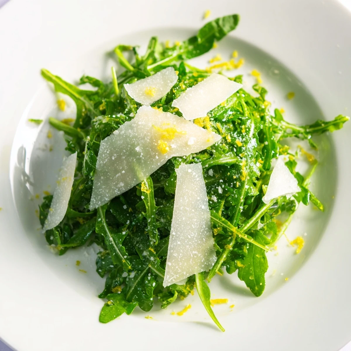 Arugula salad with lemon dressing, a fresh green salad topped with shaved Parmesan.