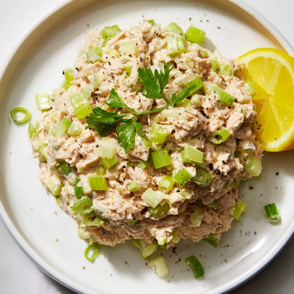 Spicy Zesty Tuna Salad, a close-up showing creamy tuna with scallions and lemon wedges, ready to eat.
