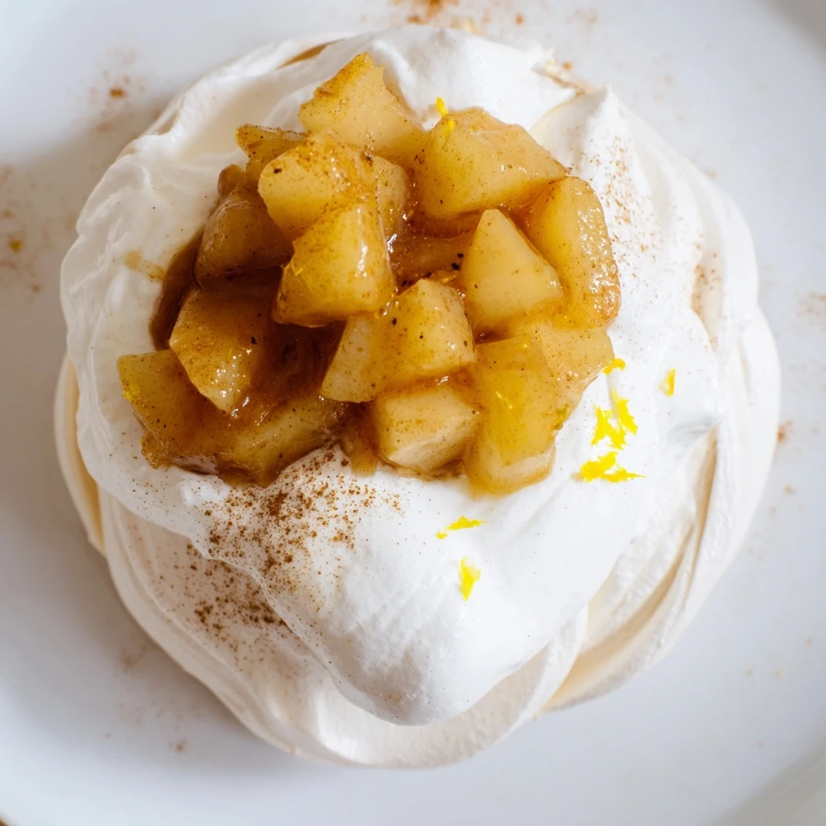 Petits pavlovas Mini Hot Toddy garnis de poires pochées au whisky et d'une crème fouettée épicée.