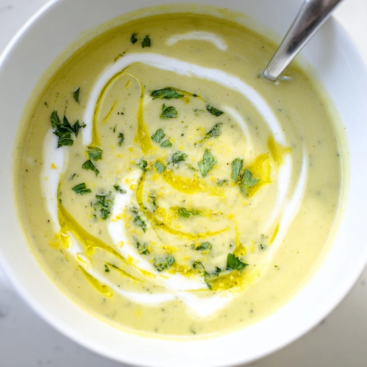 Une soupe de courgette crémeuse et lisse, garnie de feuilles de basilic frais et d'un filet d'huile d'olive.
