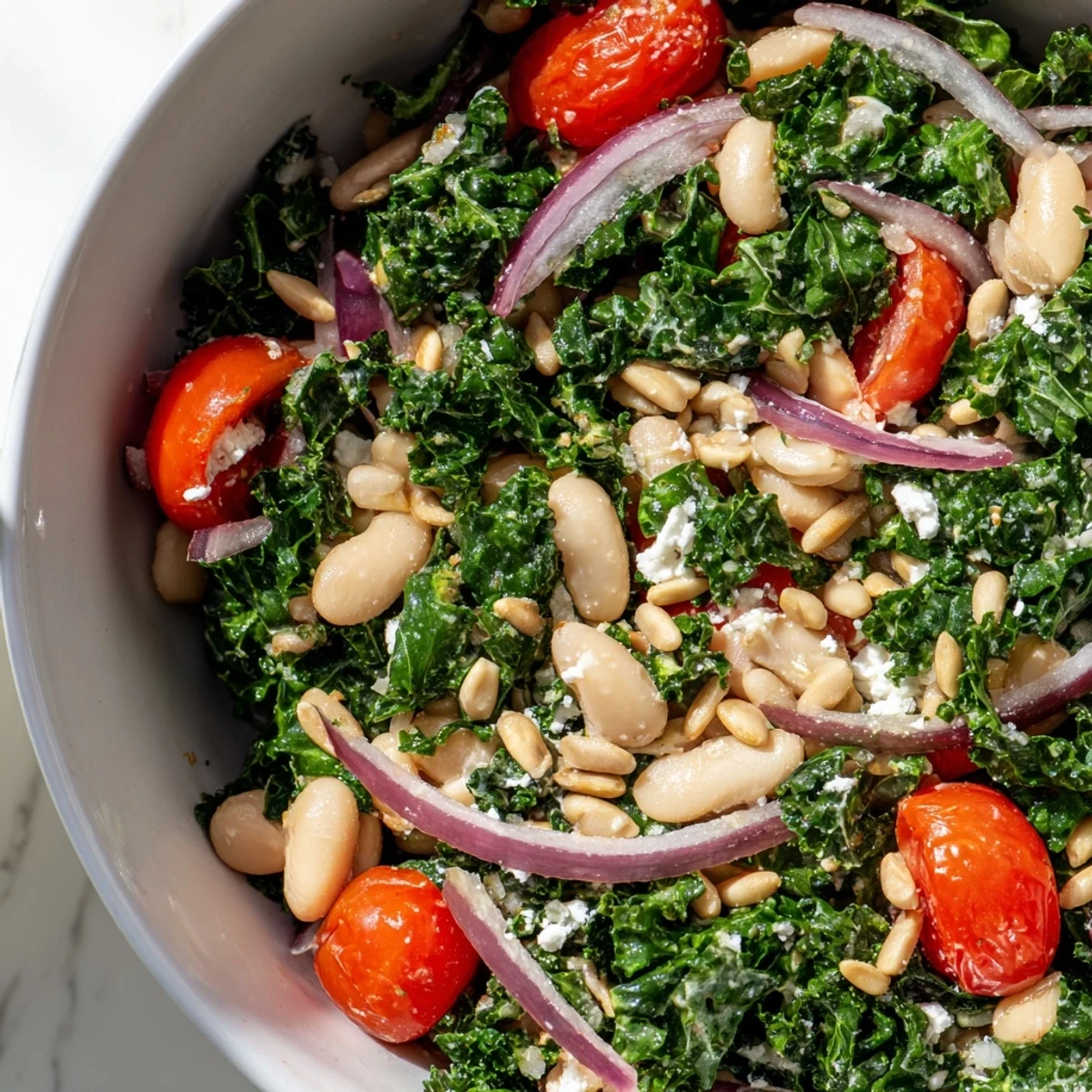 Une assiette généreuse de White Bean and Kale Salad, garnie de tomates cerises et de graines de tournesol grillées.