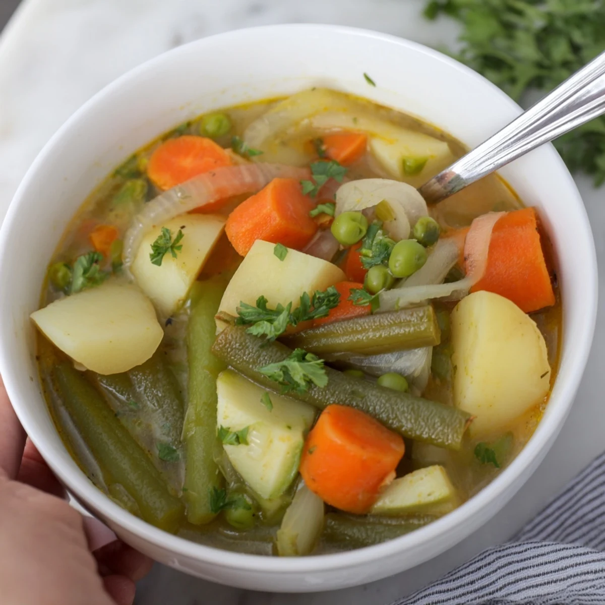 Une garniture de persil frais sur un bol fumant de soupe aux pommes de terre et légumes, servie avec du pain croustillant.