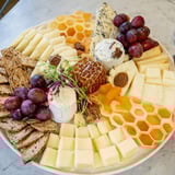 The Gilded Hive cheese board arranged with various cheeses and crackers around a honeycomb center.