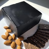 Close-up of the "Obsidian Peak," a striking cheese platter featuring black cheddar and garnished almonds.