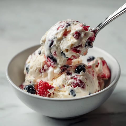 Une cuillère en argent est utilisée pour prendre une portion de crème glacée avec des fruits rouges.