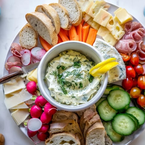 Une planche de charcuterie moderne avec un beurre à l'aneth crémeux au centre.  