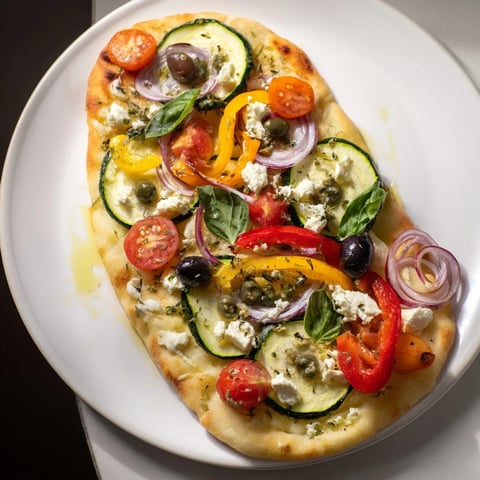 Pain plat provençal coloré garni de légumes méditerranéens et d'herbes aromatiques.  