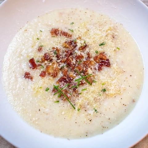 Soupe crémeuse au parmesan avec bacon croustillant, servie dans un bol chaud.  