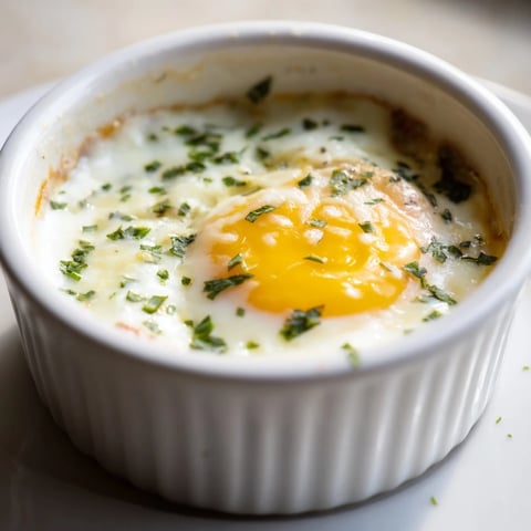 Oeufs cocotte cuits au four, crémeux et garnis d'herbes fraîches.