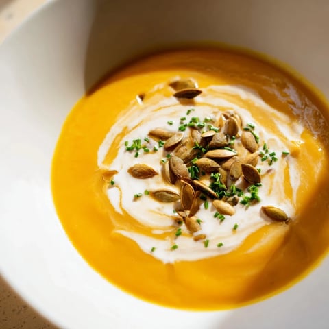 A smooth bowl of creamy Velouté de Potimarron, topped with toasted pumpkin seeds.