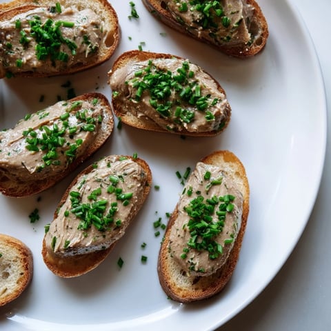 Burgundy Snail Pâté Bites drizzled with chives, a French appetizer ready to enjoy with a chilled wine.