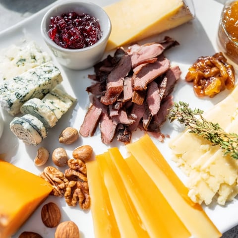 Assiette de charcuterie au renne avec fromages et accompagnements, parfaite pour un apéritif festif.