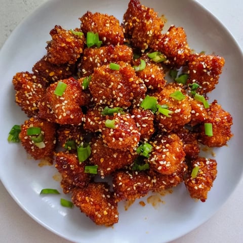 Honey-Sriracha chicken bites glistening in a sweet and spicy glaze ready for serving.