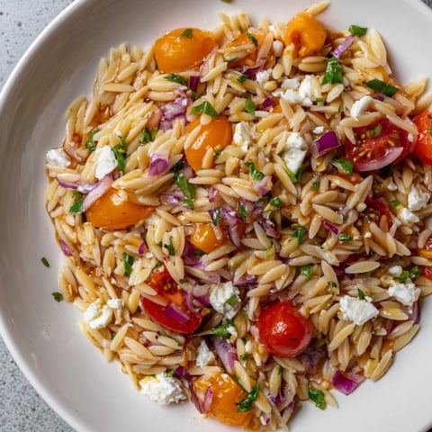 Juicy cherry tomatoes and crumbled feta highlight the Tomato Feta Orzo, a flavorful side dish.