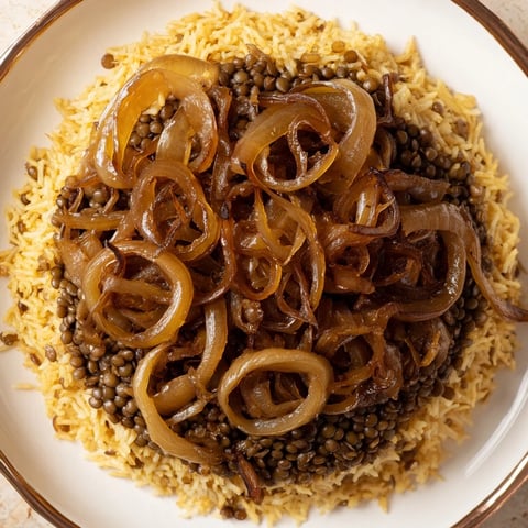 Golden caramelized onions crown a steaming bowl of Lebanese Mjadra, a hearty lentil and rice dish.