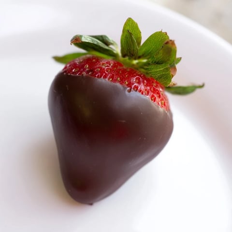 Fraisiers luisants trempés dans une ganache au chocolat noir, offrant une texture crémeuse et une touche élégante pour une soirée romantique.