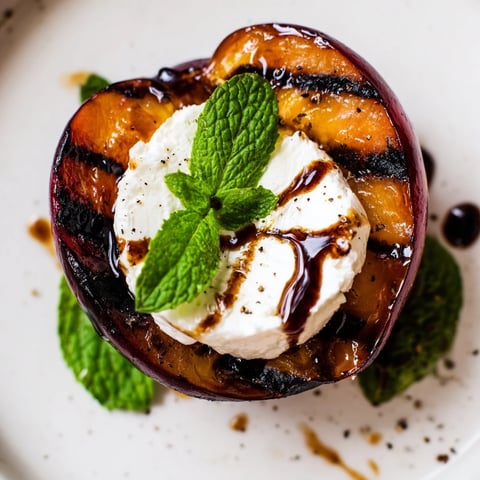 Grilled plums topped with creamy goat cheese and a drizzle of balsamic glaze on a serving platter.