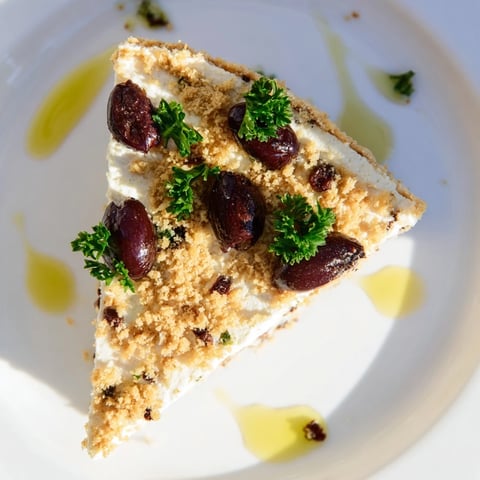 Kalamata Cheesecake Appetizer garni d'olives Kalamata émincées, de persil frais et d'un filet d'huile d'olive sur une nappe rustique.