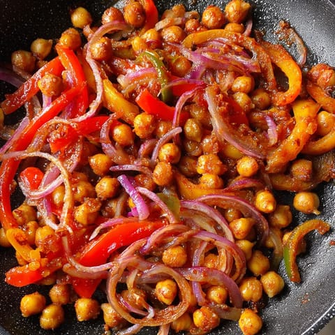 Une image de légumes cuits dans une poêle, y compris des poivrons, des carottes et des haricots.