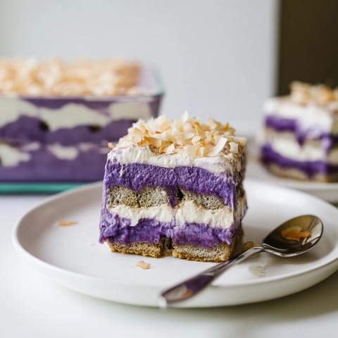 Un tiramisu violet d'ube sain, avec des couches de ladyfingers et de crème et décoré de noix de coco.