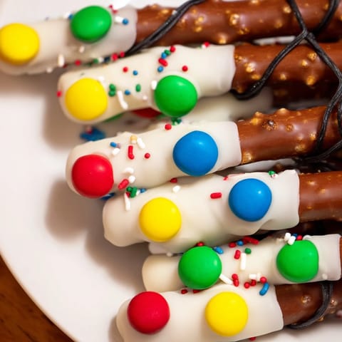 Fun no-bake snack: Pretzel sticks decorated as Christmas lights, a colorful and delicious treat.