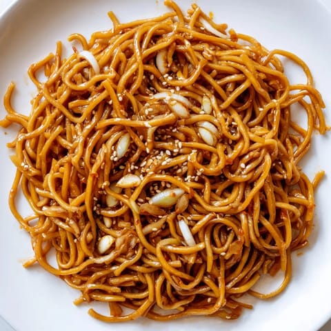 Vibrant image of Garlic Chili Oil Noodles: perfectly coated noodles with a fiery red chili oil sauce, ready to eat.
