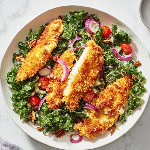 Crispy chicken kale salad with golden, crunchy chicken strips atop a bed of fresh kale.