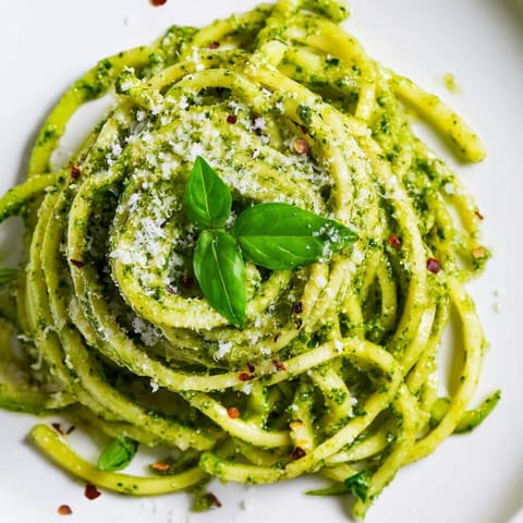 Zoodles crémeux au pesto maison, agrémentés de croûtons dorés et d'un filet d'huile d'olive, présentés dans un bol blanc.