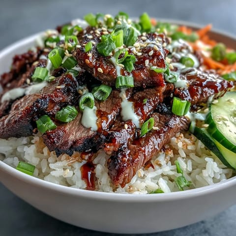 Ce bol appétissant de Korean BBQ Steak Rice Bowls présente une garniture généreuse de steak et de légumes colorés sur un lit de riz parfumé.