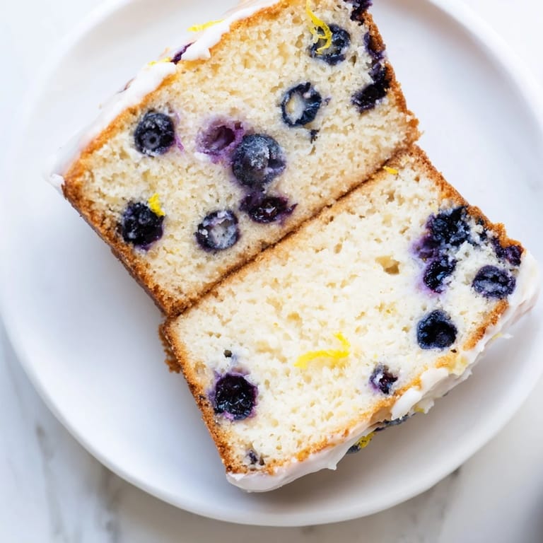 Fresh blueberries dot a golden Lemon Blueberry Yogurt Loaf, perfect with a cup of tea.