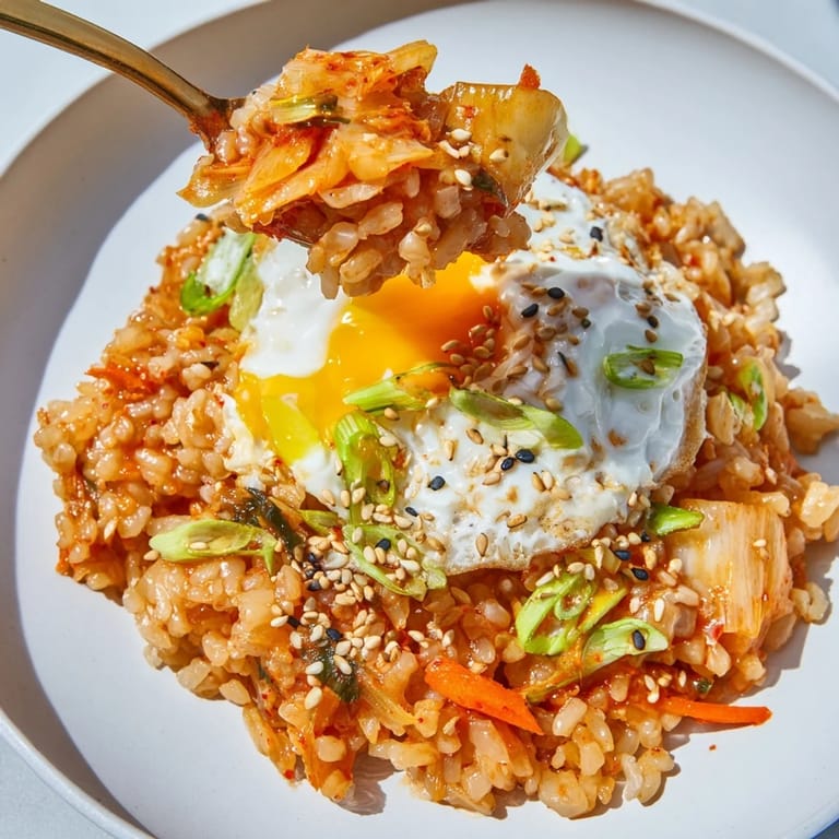 Steaming bowl of kimchi fried rice with sesame seeds, showcasing the dish's spicy Korean flavors.