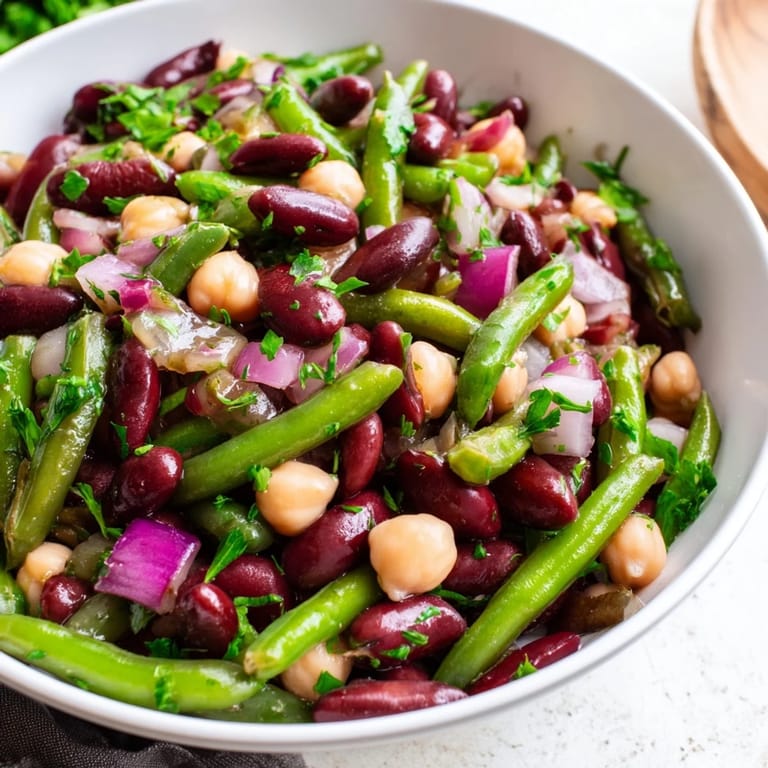 Three-Bean Salad glacé, parsemé d'oignon rouge et de persil, offrant une touche vive et acidulée.