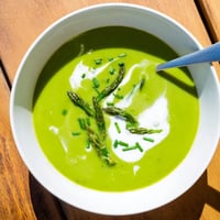 Creamy Asparagus Soup garnished with fresh chives and tender spears in a rustic bowl.