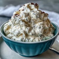 Pudding crémeux au yaourt et graines de chia avec vanille, garni de baies fraîches et de copeaux de noix de coco toastés.  