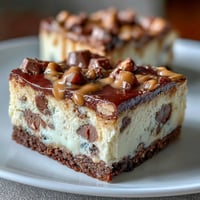 Des barres de cheesecake au beurre de cacahuète crémeux et aux mini-cups de chocolat, parfaites pour les fêtes et célébrations.