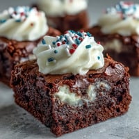 Petits brownies moelleux et fondants décorés de crème et de paillettes rouges, blanches et bleues.