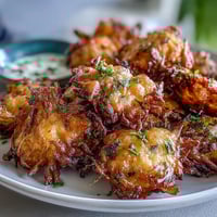 Bouchées croustillantes de fleurs de pissenlit dorées et légèrement panées, accompagnées d'une sauce aux herbes fraîches pour une entrée originale.